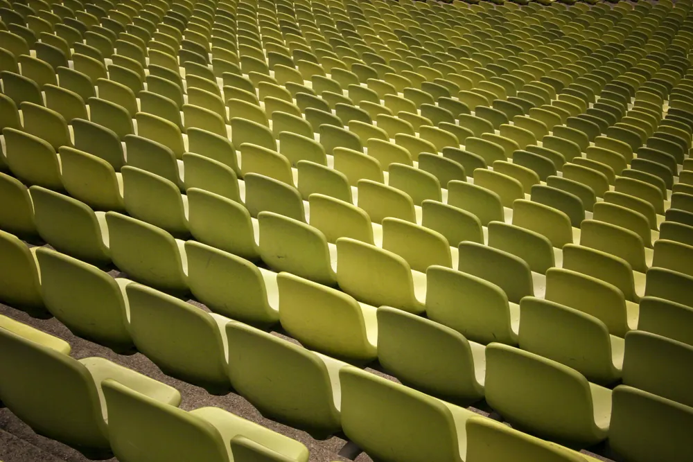 Dicht gestaffelte gelbgrüne Sitzschalen eines Stadionrangs in Nahaufnahme