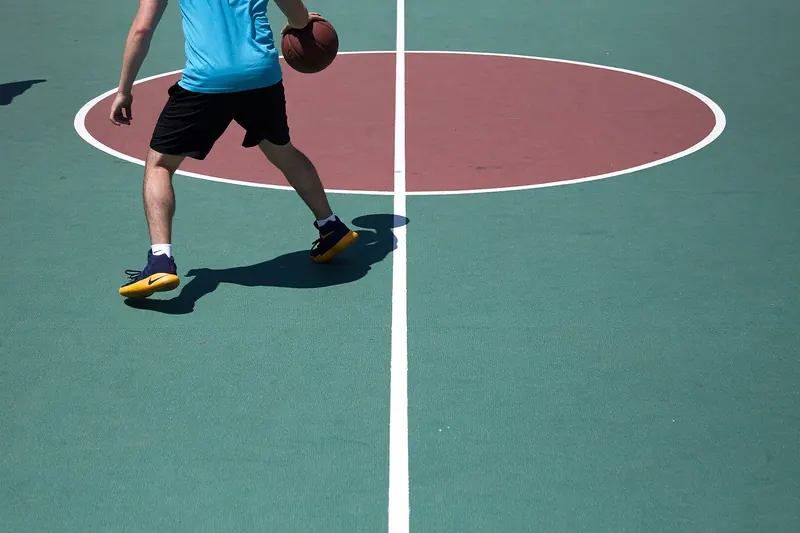 Spieler mit Ball auf einem Freiplatz mit rotem Mittelkreis, von hinten aufgenommen