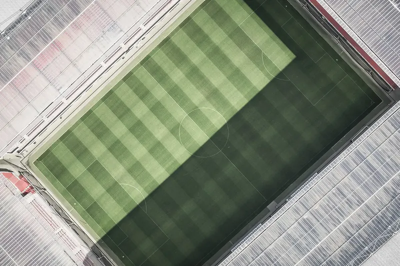Luftaufnahme eines Fußballplatzes mit gestreiftem Rasen und leeren Rängen