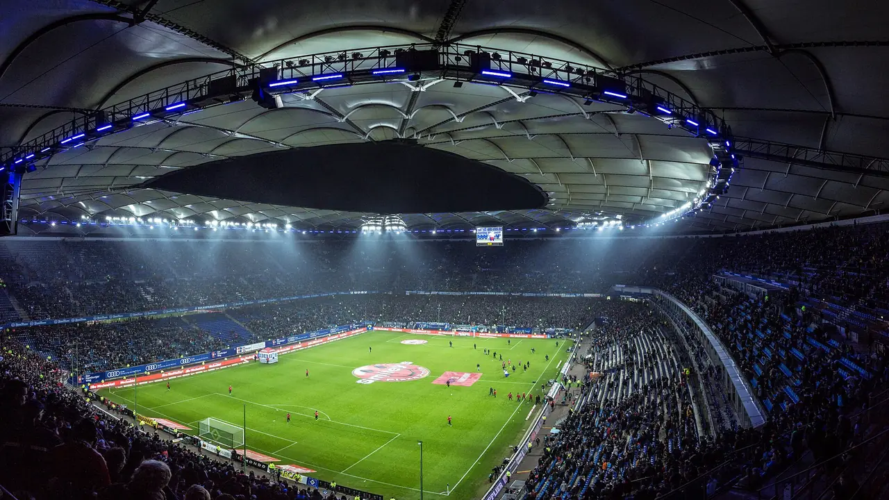 Ausverkaufte Ränge und Flutlicht über einem Fußballstadion bei Nacht